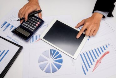 business documents on office table with smart phone and digital tablet and man working in the background.